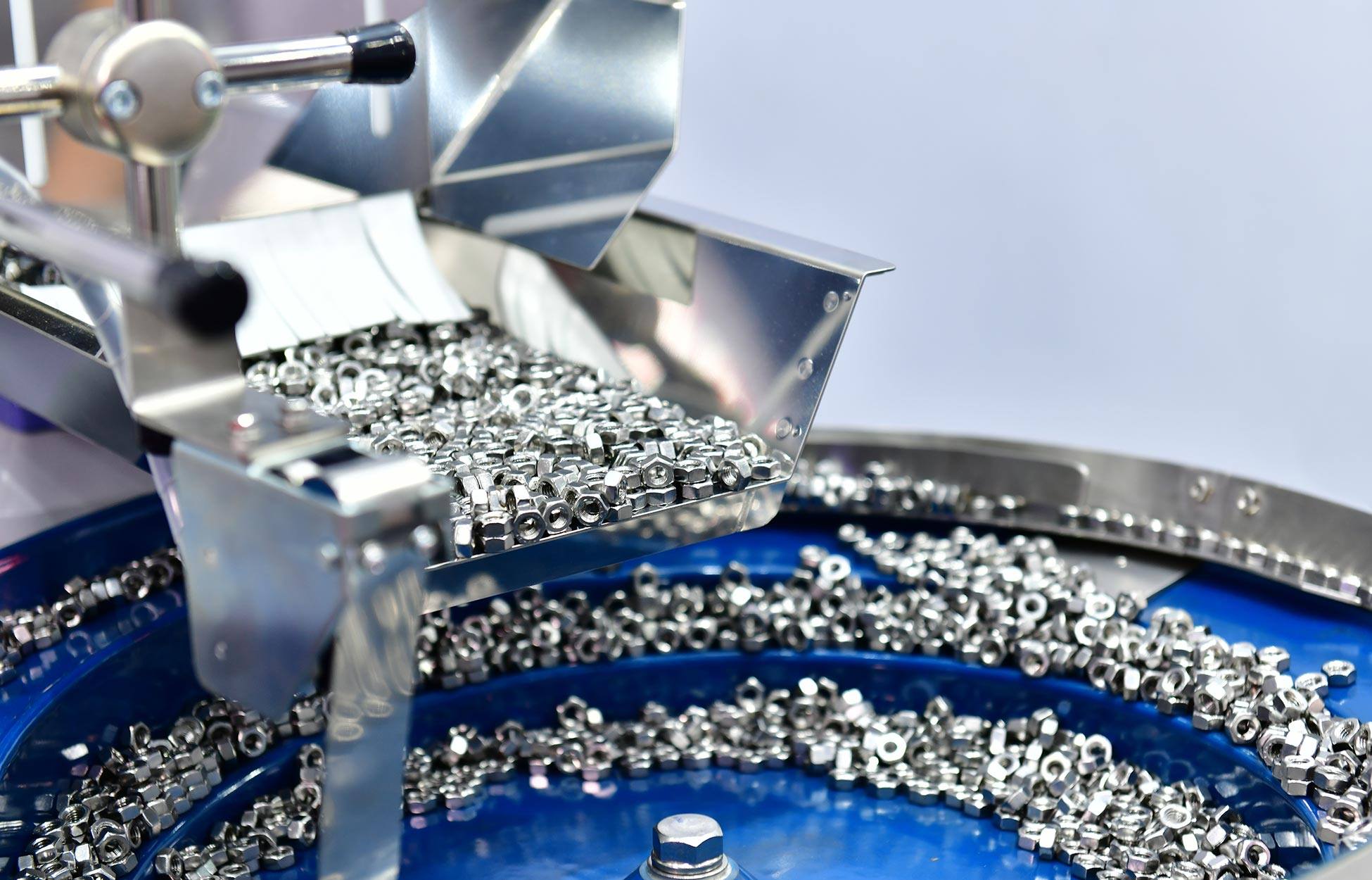 A silver machine producing small metal pieces that are compiled in a blue circle